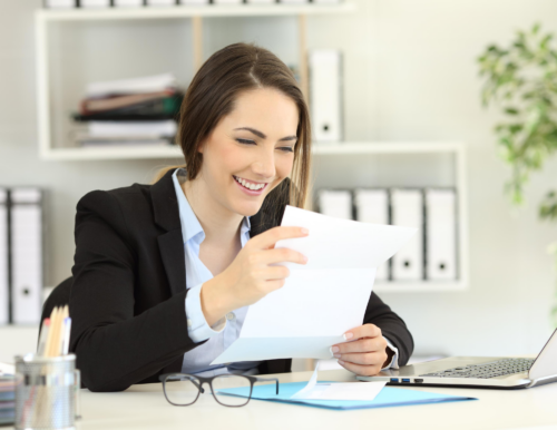 smiling business woman reading mail at her desk