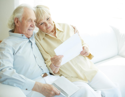 older couple reviewing direct mail for insurance on couch