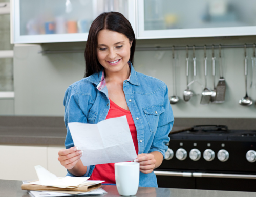 woman reading mail from digital mailer campaign in kitchen