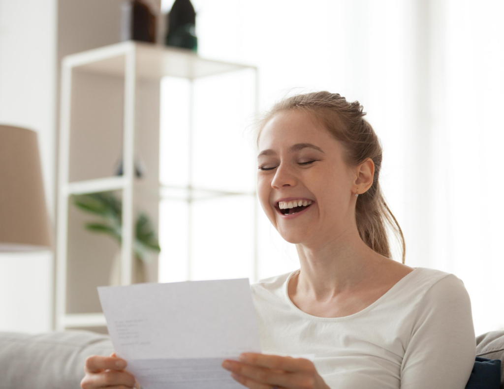 young woman reading college acceptance letter at home